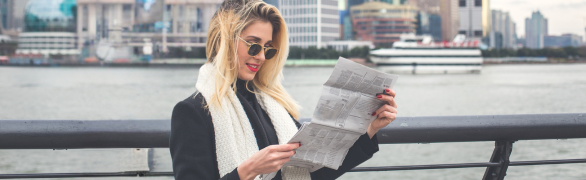 Woman reading newspaper at pier