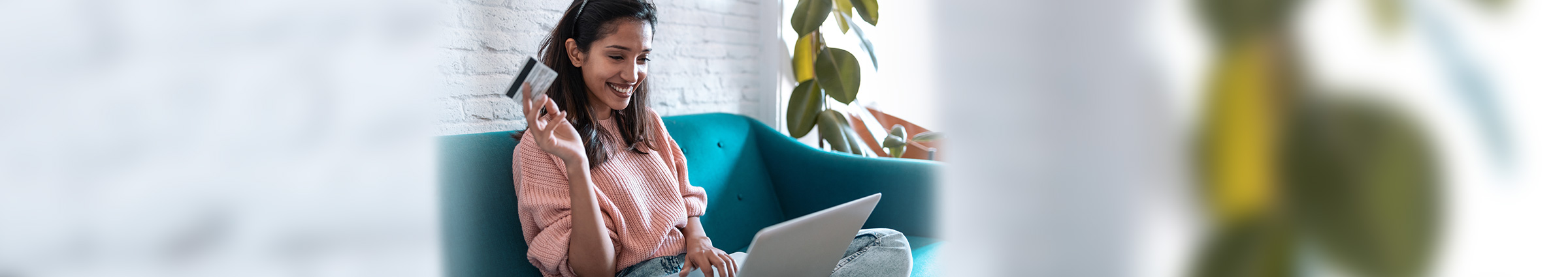 Young woman on a laptop with a credit card in her hand