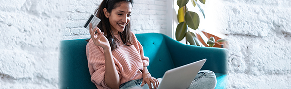 Young woman on a laptop with a credit card in her hand