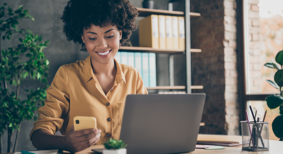 Woman using phone at computer